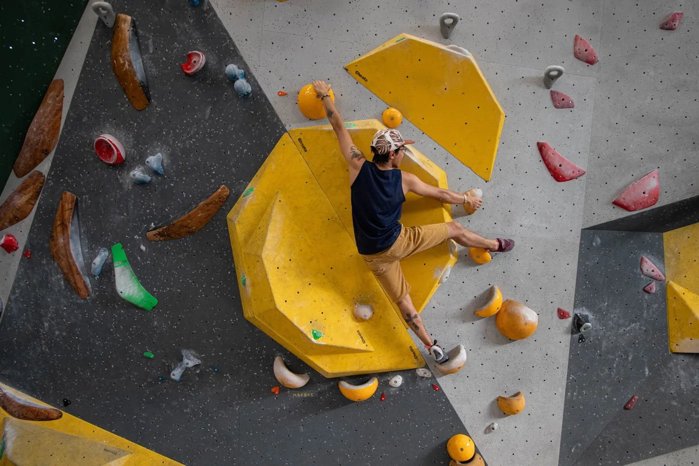 Person klettert an einer bunten Boulderwand
