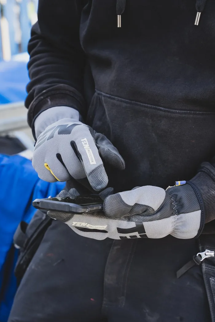 Tradesperson wearing work gloves using a smartphone
