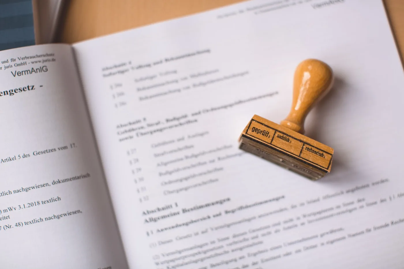 Aufgeschlagenes Gesetzbuch mit einem Holzstempel darauf