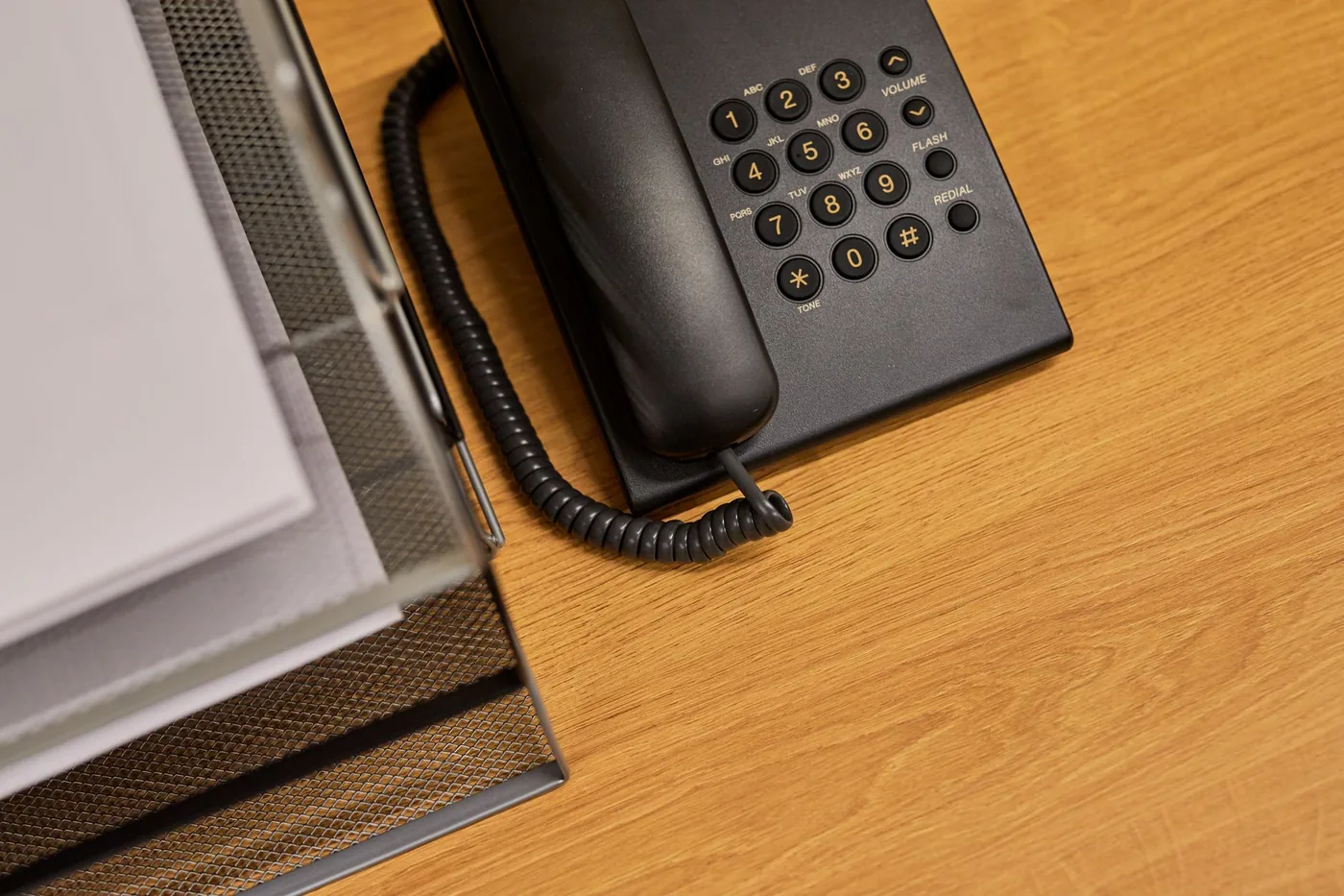 Black office telephone on a desk next to a document tray