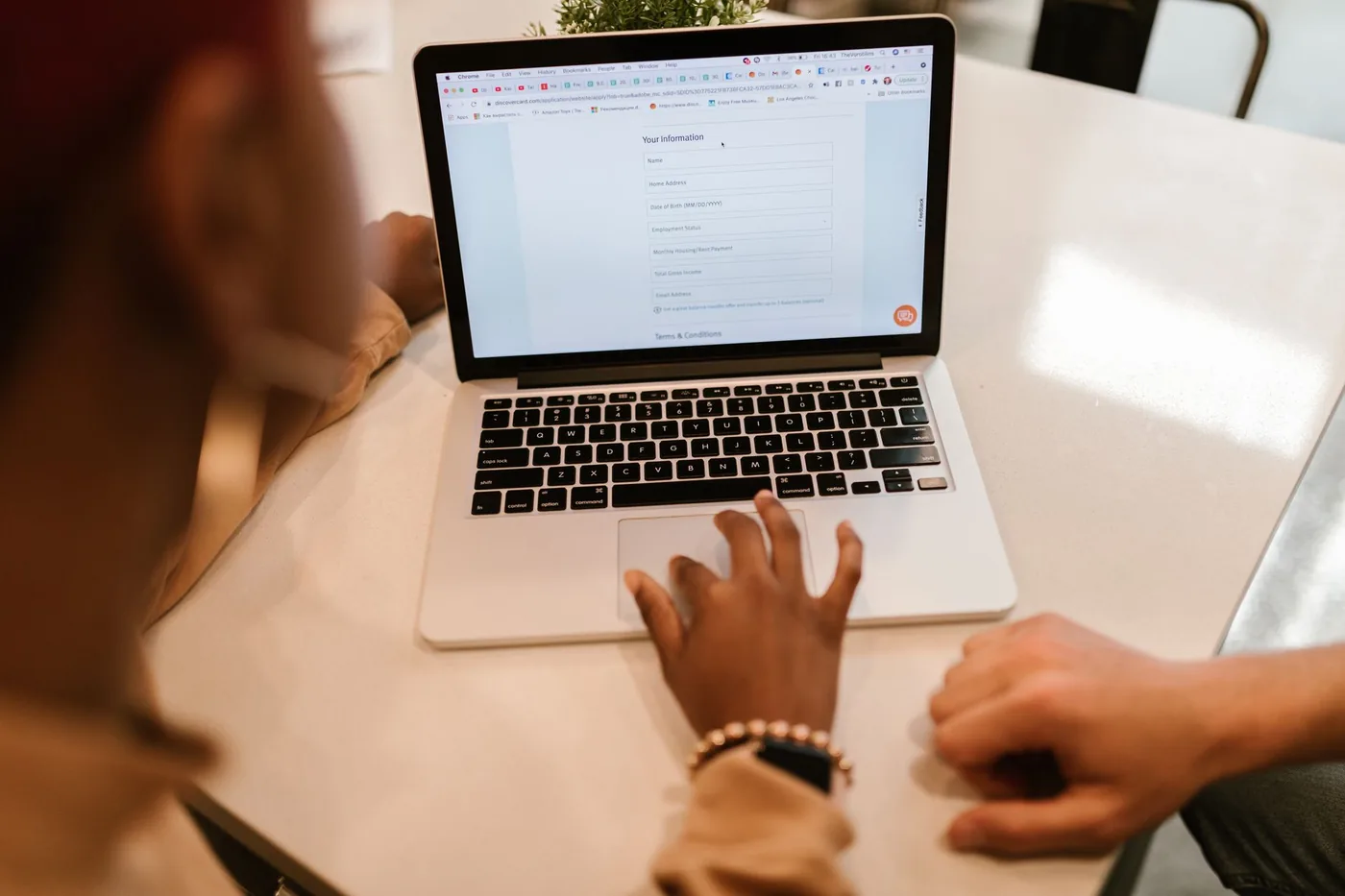 Hands on a laptop showing a form with input fields