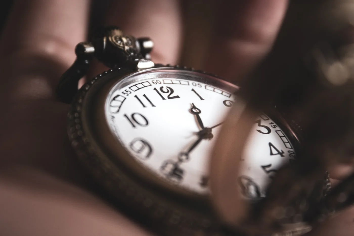 Alte Taschenuhr mit weissem Zifferblatt in einer Hand
