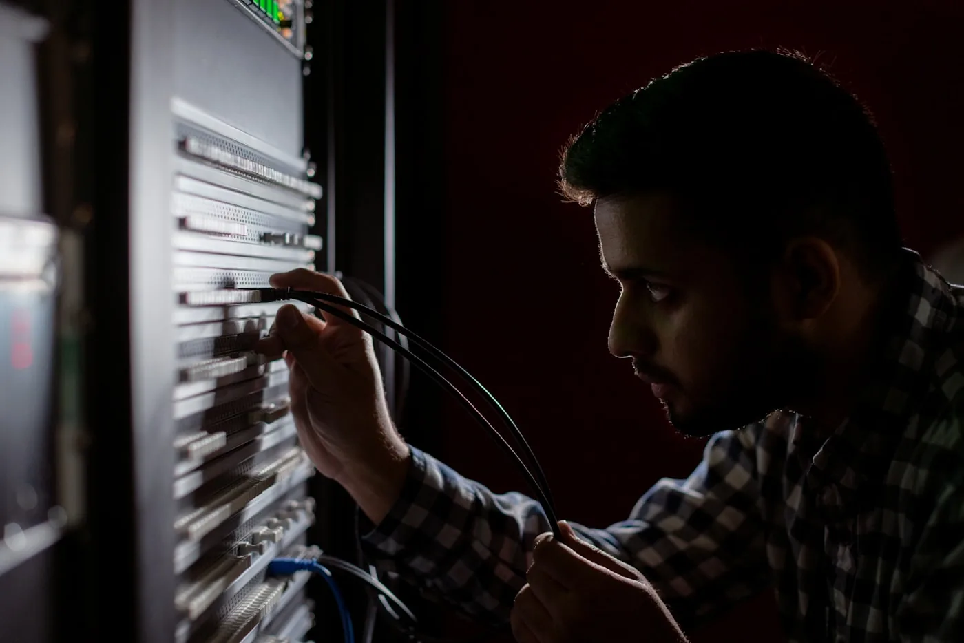 Techniker steckt Kabel in ein Netzwerk-Patchfeld im Serverschrank