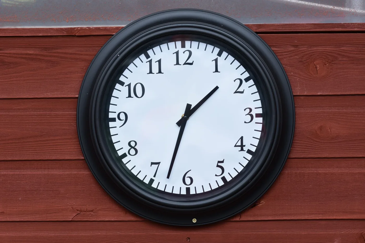 Black-framed wall clock on a wooden wall