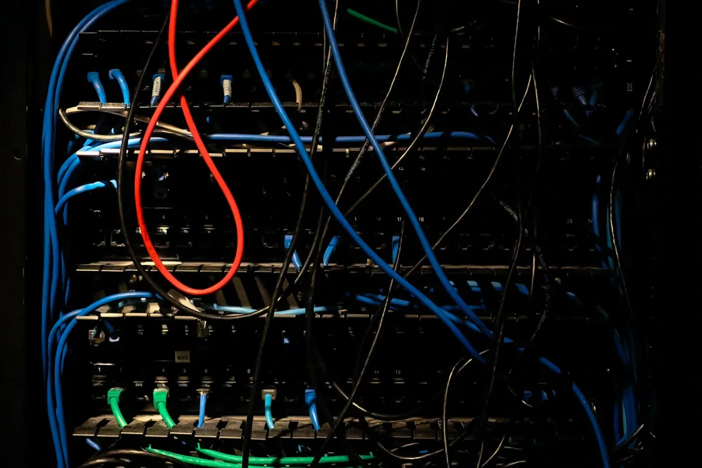 Netzwerkschrank mit Patchfeldern und bunten Netzwerkkabeln im Halbdunkel